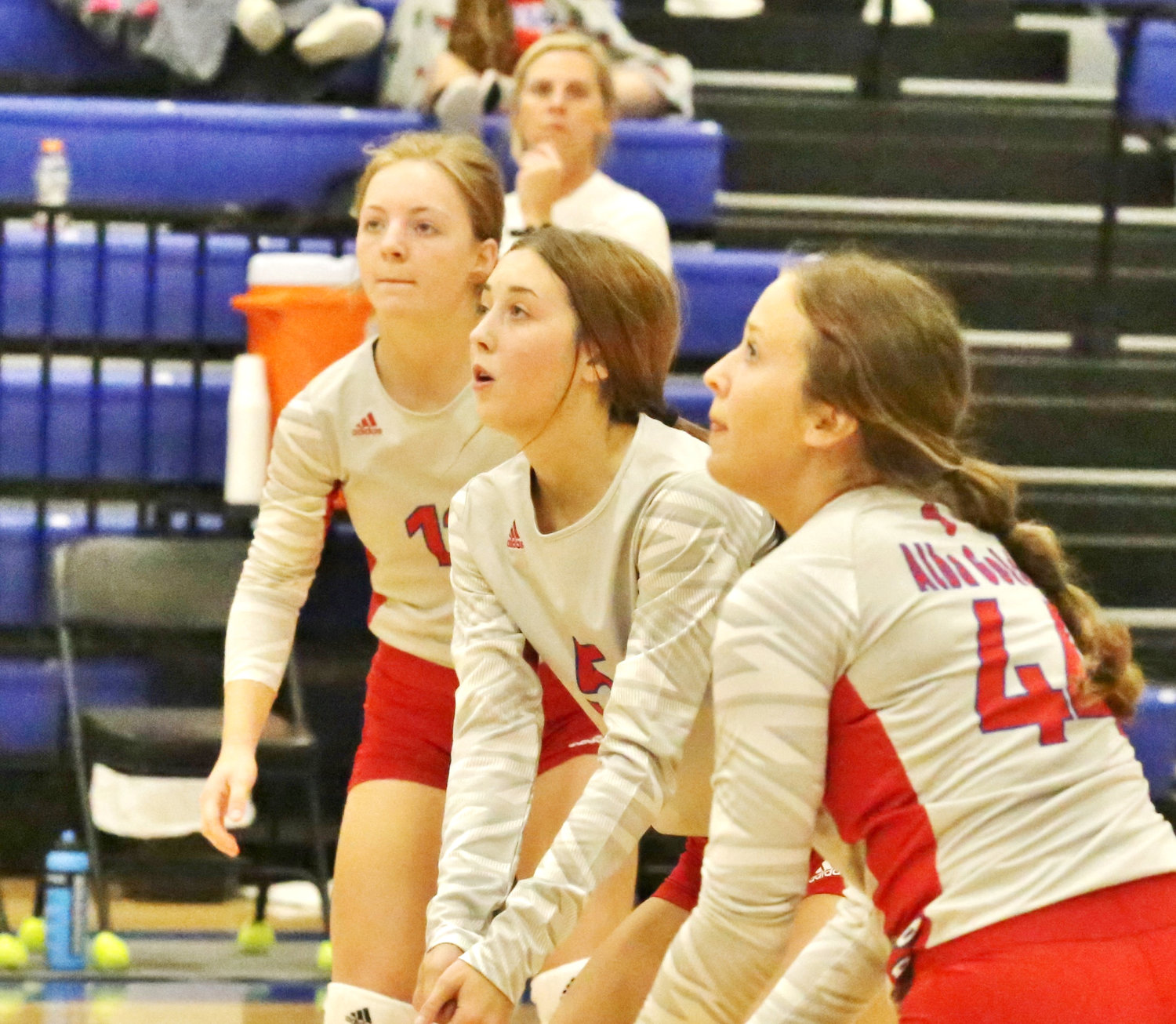 The Alba-Golden back line readies to dig a serve. From left Cacie Lennon, Kamrin Wright and Skyler West. In the background Coach Jamie Webster anticipates the action.